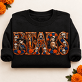 Folded black Chicago Bears Day of the Dead crewneck sweatshirt with rolled sleeves, sugar skull artwork and orange marigolds