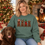 Woman wearing heather green Chocolate Lab Christmas sweatshirt beside a chocolate Labrador in a Christmas living room
