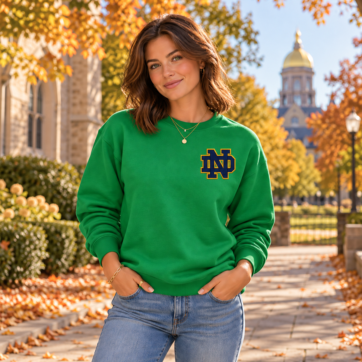Female model wearing Irish Green Notre Dame Sweater with enlarged left-chest print and gold necklaces